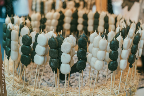 closeup shot of many Japanese black and white dango sticks grilled on fire at a traditional sweet snack stall in kuromon ichiba market in Osaka japan photo