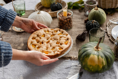 Hands of woman picking up plate with homemade pumpkin pie photo