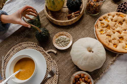 Hand of woman eating pumpkin porridge at autumnal table photo