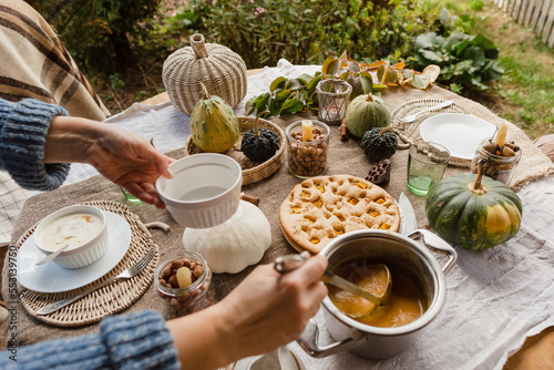 Hands of woman pouring porridge at autumnal table photo