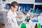 Blond child wearing scientist uniform measuring liquid at laboratory