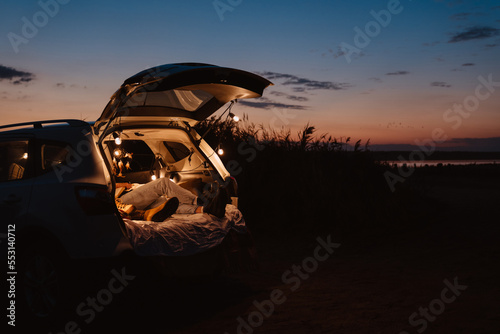 Happy young couple lying together in car by seaside