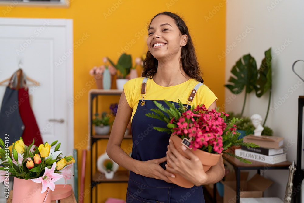 Young african american woman florist smiling confident holding plant at flower shop Young african american woman florist smiling confident holding plant at flower shop
