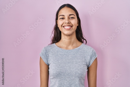 Young brazilian woman wearing casual t shirt over pink background with a happy and cool smile on face. lucky person.