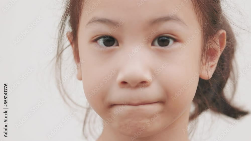 Face close up of adorable asian girl kid who is happily and naturally looking with positive emotion on white background shows beautifulness of childhood with cheerful and enjoy emotion. Face close up of adorable asian girl kid who is happily and naturally looking with positive emotion on white background shows beautifulness of childhood with cheerful and enjoy emotion.
