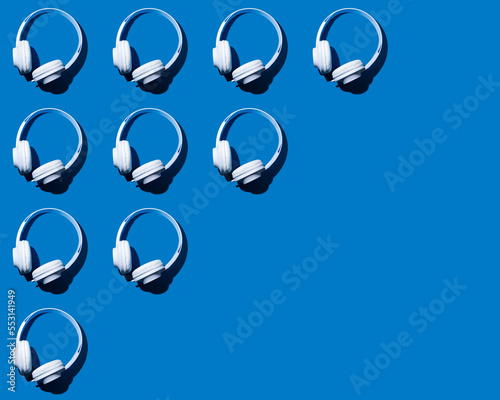 Rows of headphones flat laid against blue background