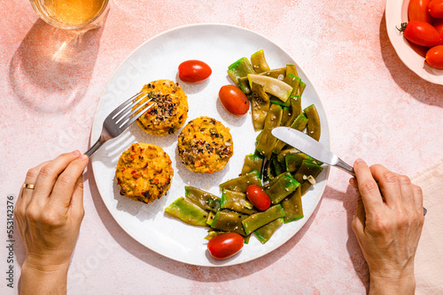 Personal perspective of woman eating rice muffins with cherry tomato and green bean salad photo