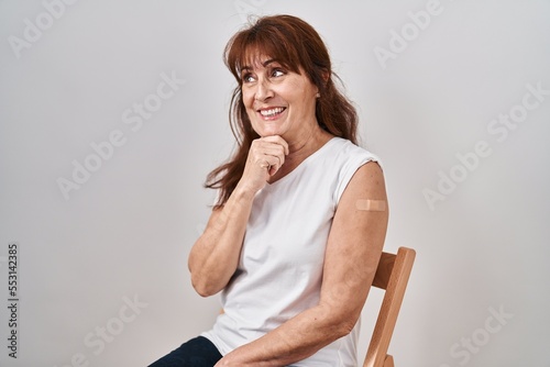 Fototapete Middle age hispanic woman getting vaccine showing arm with band aid with hand on chin thinking about question, pensive expression