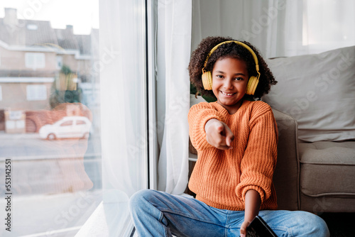 Happy girl wearing wireless headphones gesturing at home photo