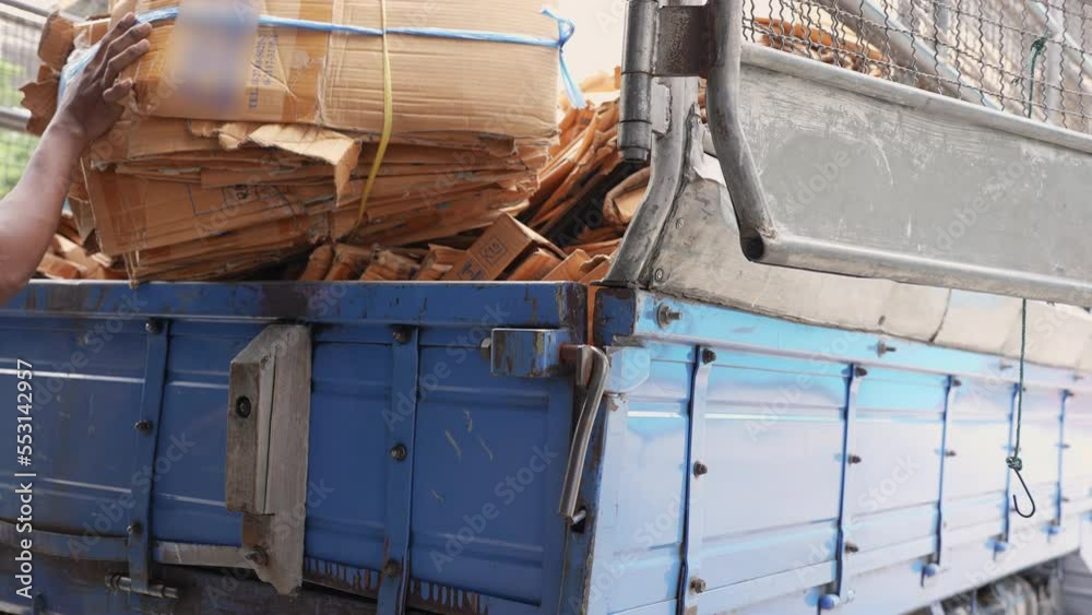 Man loads cardboard boxes scraps into the back of a truck to recycling factory. Selective focus at back of truck. Man loads cardboard boxes scraps into the back of a truck to recycling factory. Selective focus at back of truck.