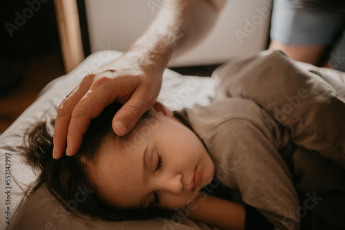 Father caressing son sleeping on bed at home photo