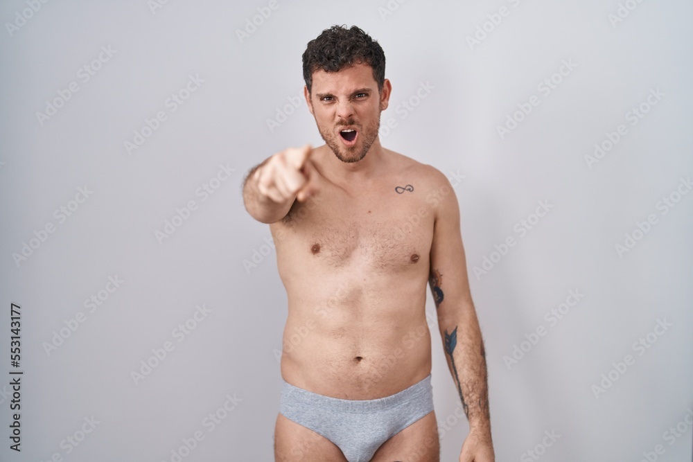 Young hispanic man standing shirtless wearing underware pointing displeased and frustrated to the camera, angry and furious with you