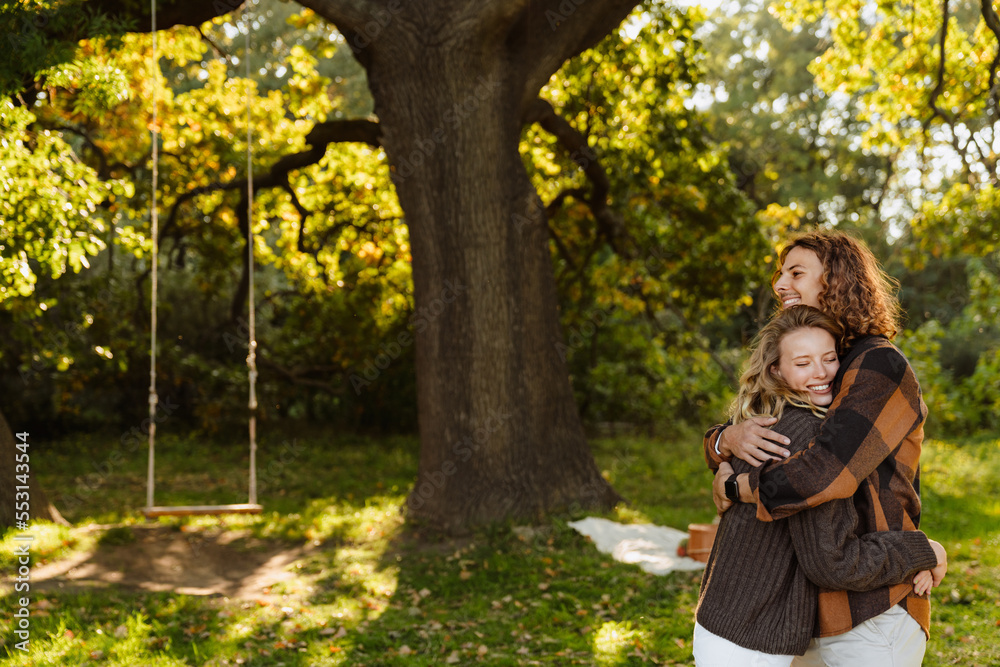 Young loving couple hugging while standing outdoors in park Young loving couple hugging while standing outdoors in park