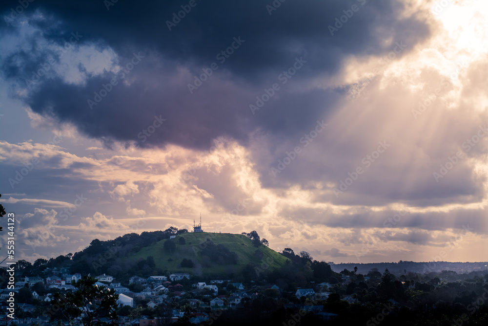 Sunlight breaking through dark clouds over historical suburb of Devonport. Auckland, New Zealand