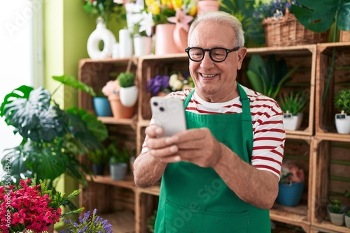 Middle age grey-haired man florist smiling confident using smartphone at flower shop