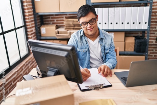 Down syndrome man ecommerce business worker writing on document at office