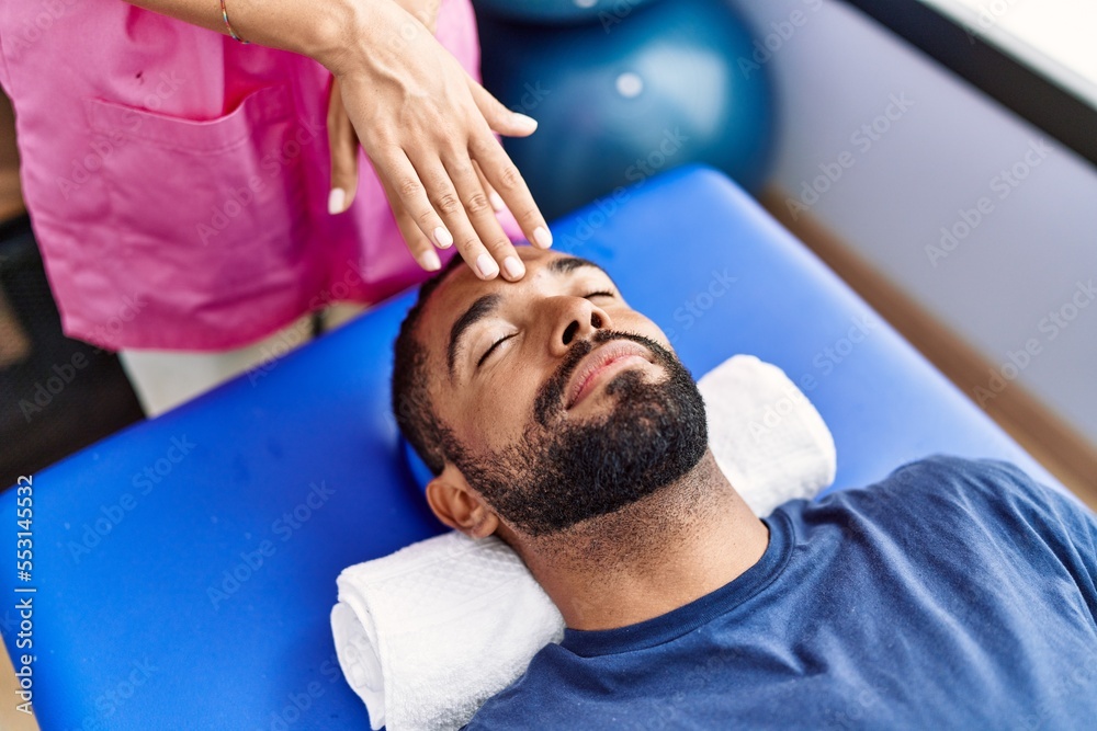 Man and woman wearing physiotherapist uniform having reiki session at physiotherpy clinic Man and woman wearing physiotherapist uniform having reiki session at physiotherpy clinic