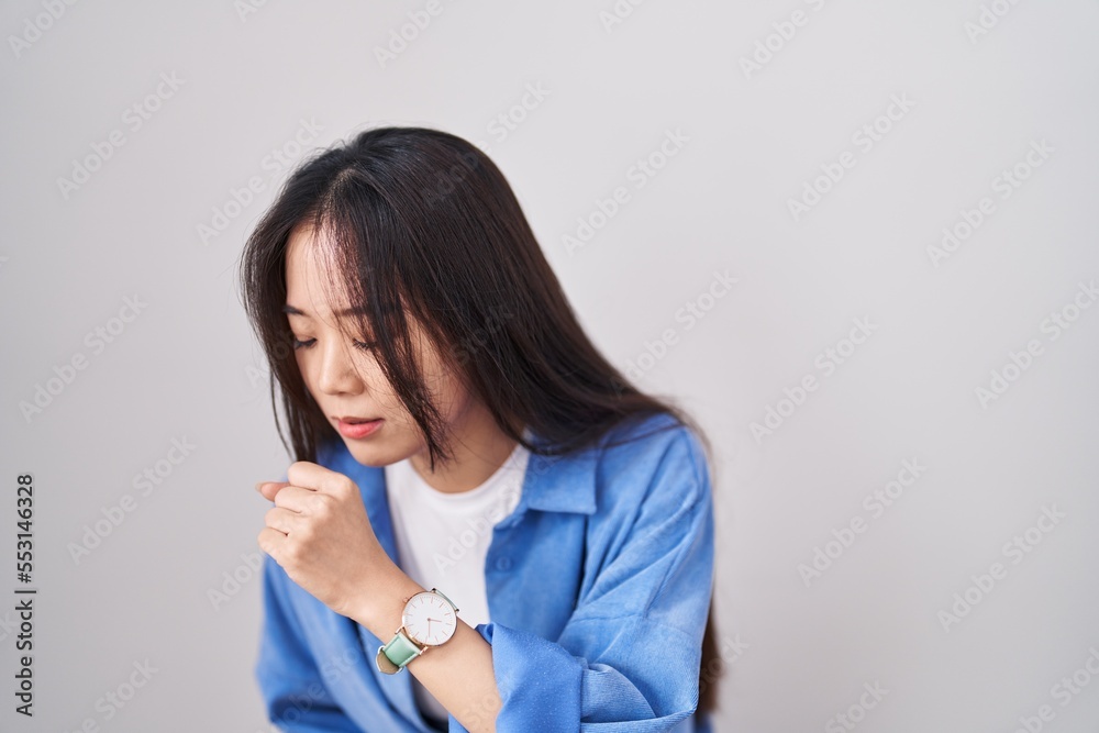 Young chinese woman standing over white background feeling unwell and coughing as symptom for cold or bronchitis. health care concept. Young chinese woman standing over white background feeling unwell and coughing as symptom for cold or bronchitis. health care concept.