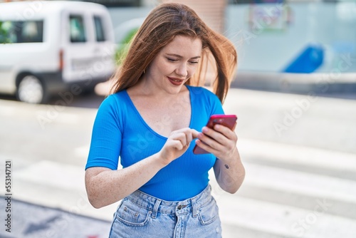 Young redhead woman smiling confident using smartphone at street