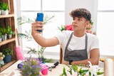 Young hispanic teenager florist make selfie by smartphone at flower shop