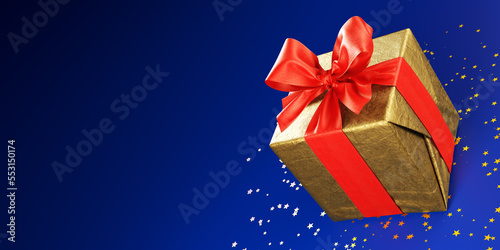 Golden Christmas gift decoration with red bow on a blue background.