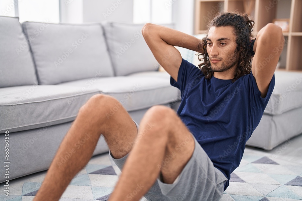 Young hispanic man training abs exercise at home Young hispanic man training abs exercise at home