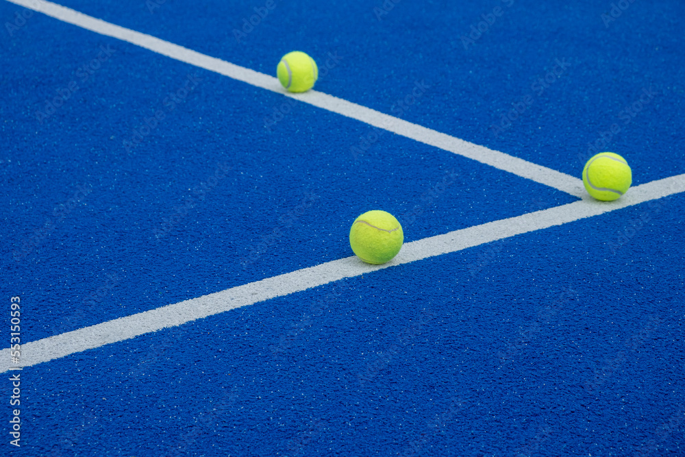 three balls on the lines of a paddle tennis court