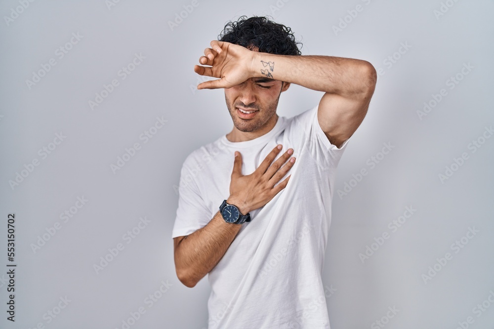 Hispanic man standing over isolated background touching forehead for illness and fever, flu and cold, virus sick Hispanic man standing over isolated background touching forehead for illness and fever, flu and cold, virus sick