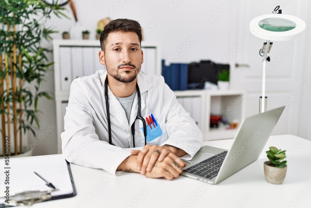 Young doctor working at the clinic using computer laptop depressed and worry for distress, crying angry and afraid. sad expression.