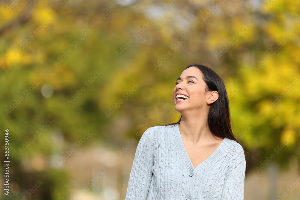Happy woman walking in a park laughing looking at side Happy woman walking in a park laughing looking at side