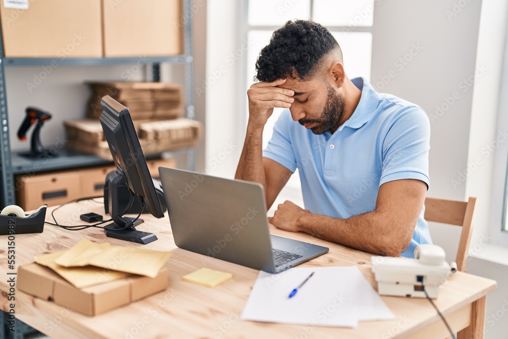 Young hispanic man ecommerce business worker stressed working at office