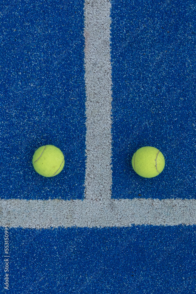two balls on a blue paddle tennis court
