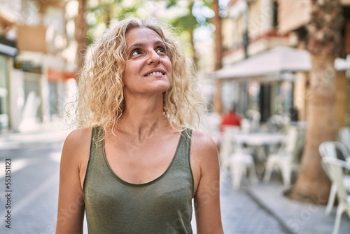 Middle age blonde woman smiling confident walking at street