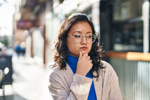 Young chinese woman standing with doubt expression at street