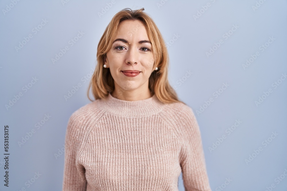 Hispanic woman standing over blue background relaxed with serious expression on face. simple and natural looking at the camera. Hispanic woman standing over blue background relaxed with serious expression on face. simple and natural looking at the camera.