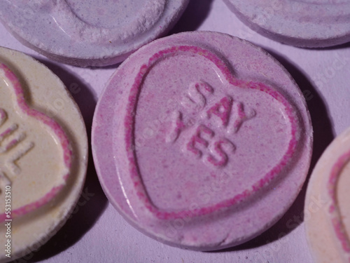 Say yes message on love heart candy on pink background close up macro shot  photo