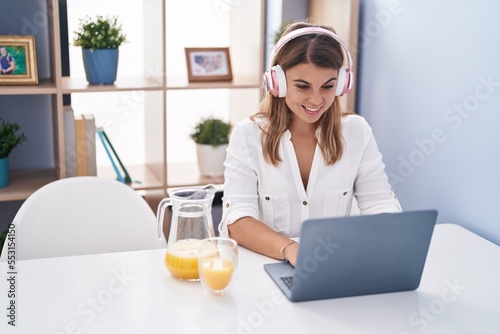 Young woman using laptp drinking orange juice at home photo