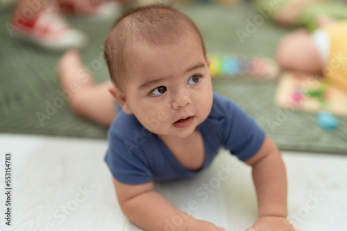 Adorable chinese toddler smiling confident crawling on floor at home