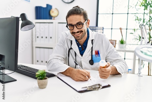 Handsome hispanic man working as doctor writing pills presciption at hospital clinic