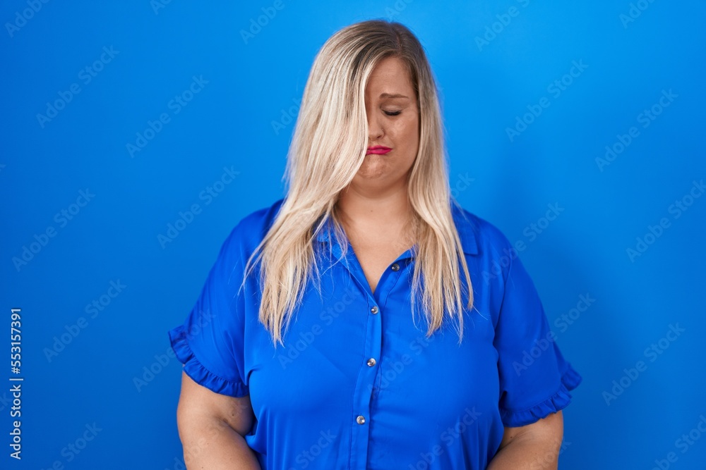 Caucasian plus size woman standing over blue background depressed and worry for distress, crying angry and afraid. sad expression. Caucasian plus size woman standing over blue background depressed and worry for distress, crying angry and afraid. sad expression.