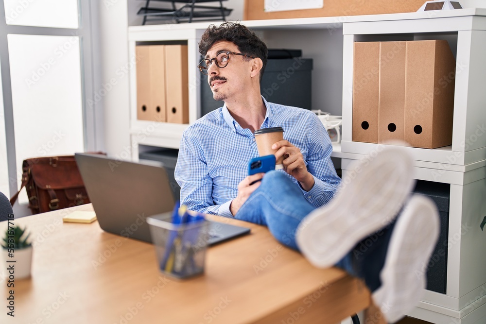 Young caucasian man business worker using smartphone drinking coffee at office Young caucasian man business worker using smartphone drinking coffee at office
