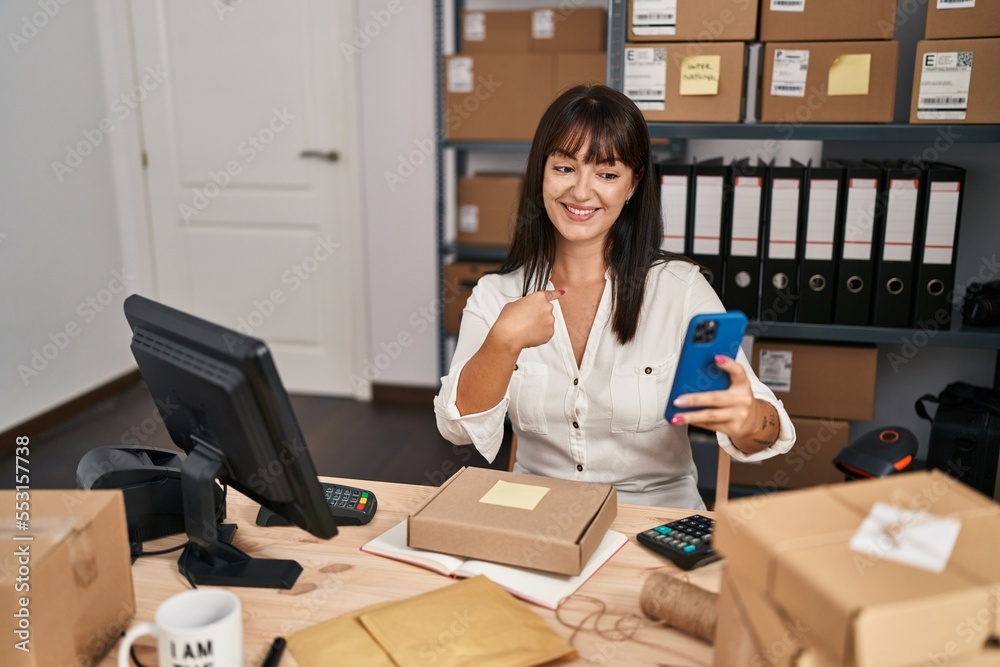 Young brunette woman working at small business ecommerce using smartphone pointing finger to one self smiling happy and proud Young brunette woman working at small business ecommerce using smartphone pointing finger to one self smiling happy and proud