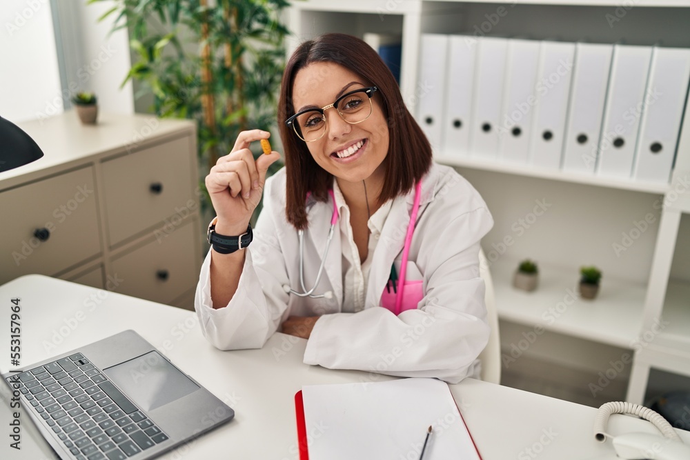 Young beautiful hispanic woman doctor smiling confident holding pill at clinic Young beautiful hispanic woman doctor smiling confident holding pill at clinic