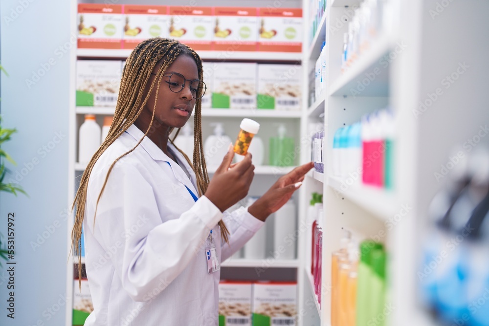 African american woman pharmacist holding pills bottle at pharmacy