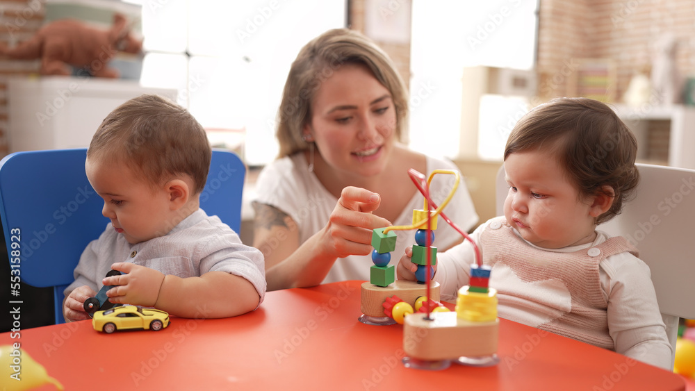 Teacher and preschool students playing with toys sitting on table at kindergarten Teacher and preschool students playing with toys sitting on table at kindergarten