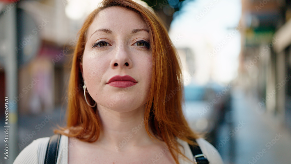 Young redhead woman with relaxed expression standing at street Young redhead woman with relaxed expression standing at street