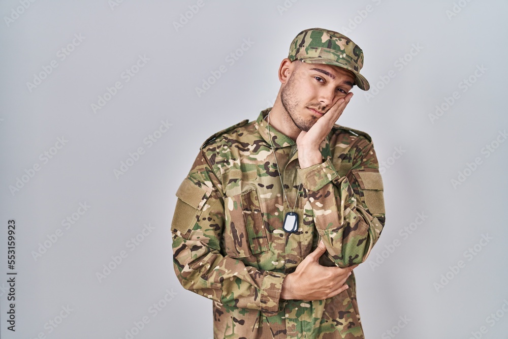 Young hispanic man wearing camouflage army uniform thinking looking tired and bored with depression problems with crossed arms. Young hispanic man wearing camouflage army uniform thinking looking tired and bored with depression problems with crossed arms.