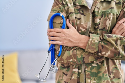 Fotografie Young hispanic man army soldier doctor holding stethoscope at home