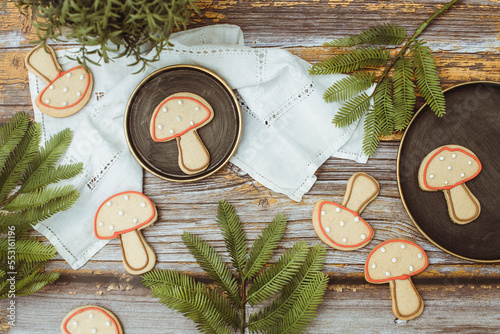 Overhead view of gingerbread mushroom cookies on a wooden table with fir branches and a lace tablecloth photo