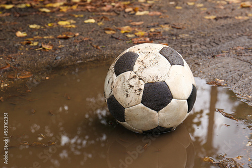 Dirty soccer ball in muddy puddle, space for text © New Africa
